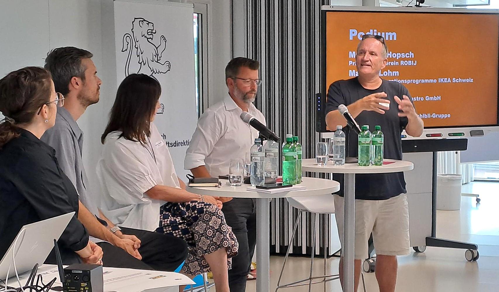 Zwei Referenten sind am Sprechen, die anderen schauen zu.