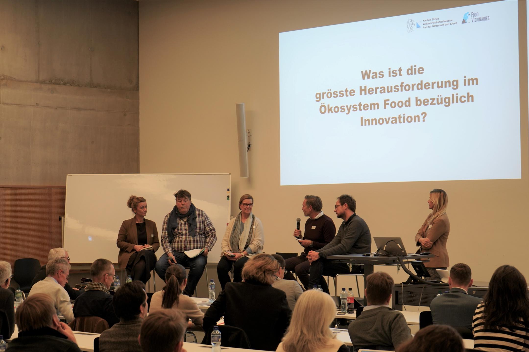 Fünf Panelisten und die Moderatorin in der Diskussion