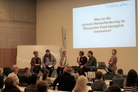 Fünf Panelisten und die Moderatorin in der Diskussion