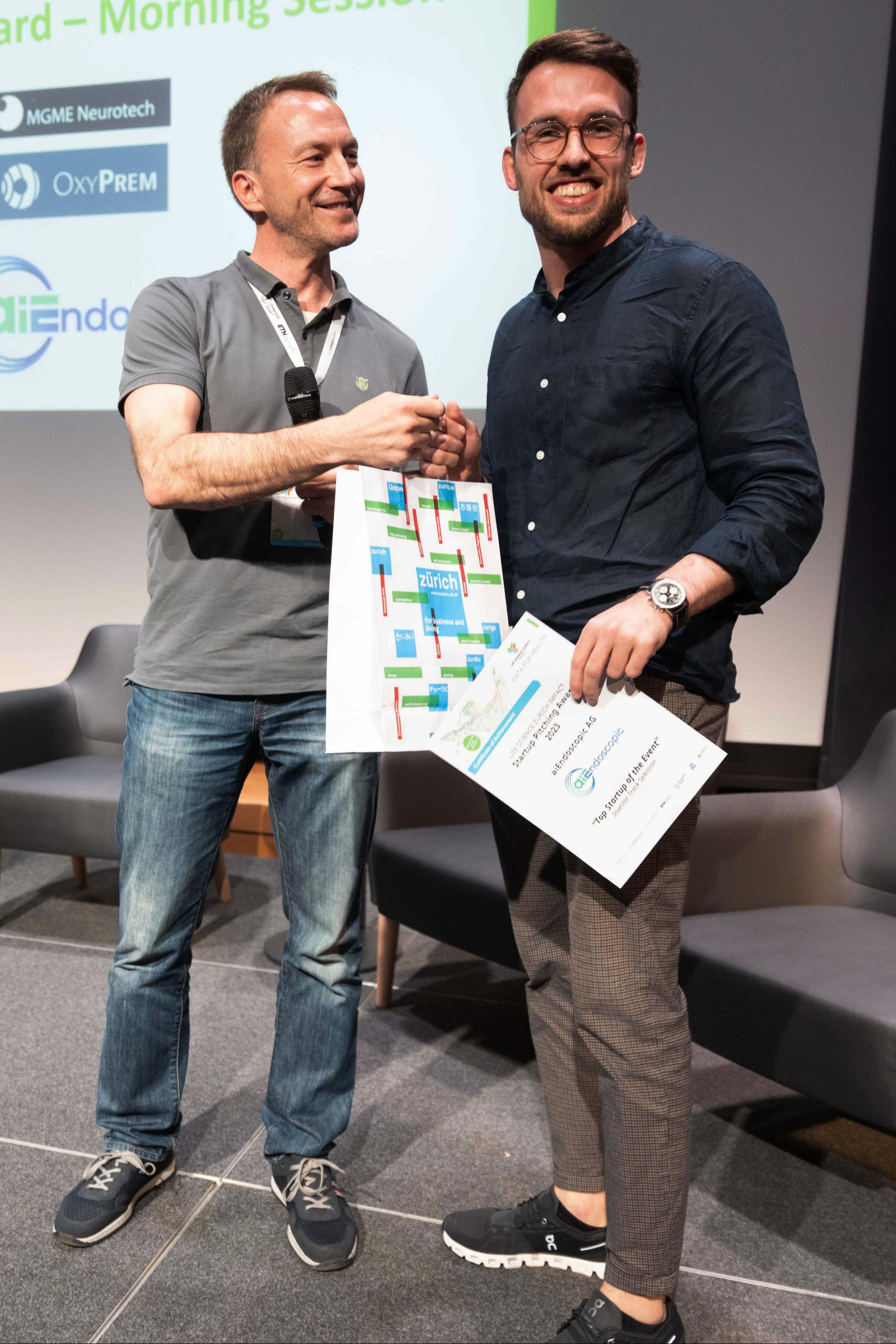 Chris Russ (ZHAW) überreicht Publikums Award an aiEndoscopic AG an der Life Science Zurich Impact Conference 2023