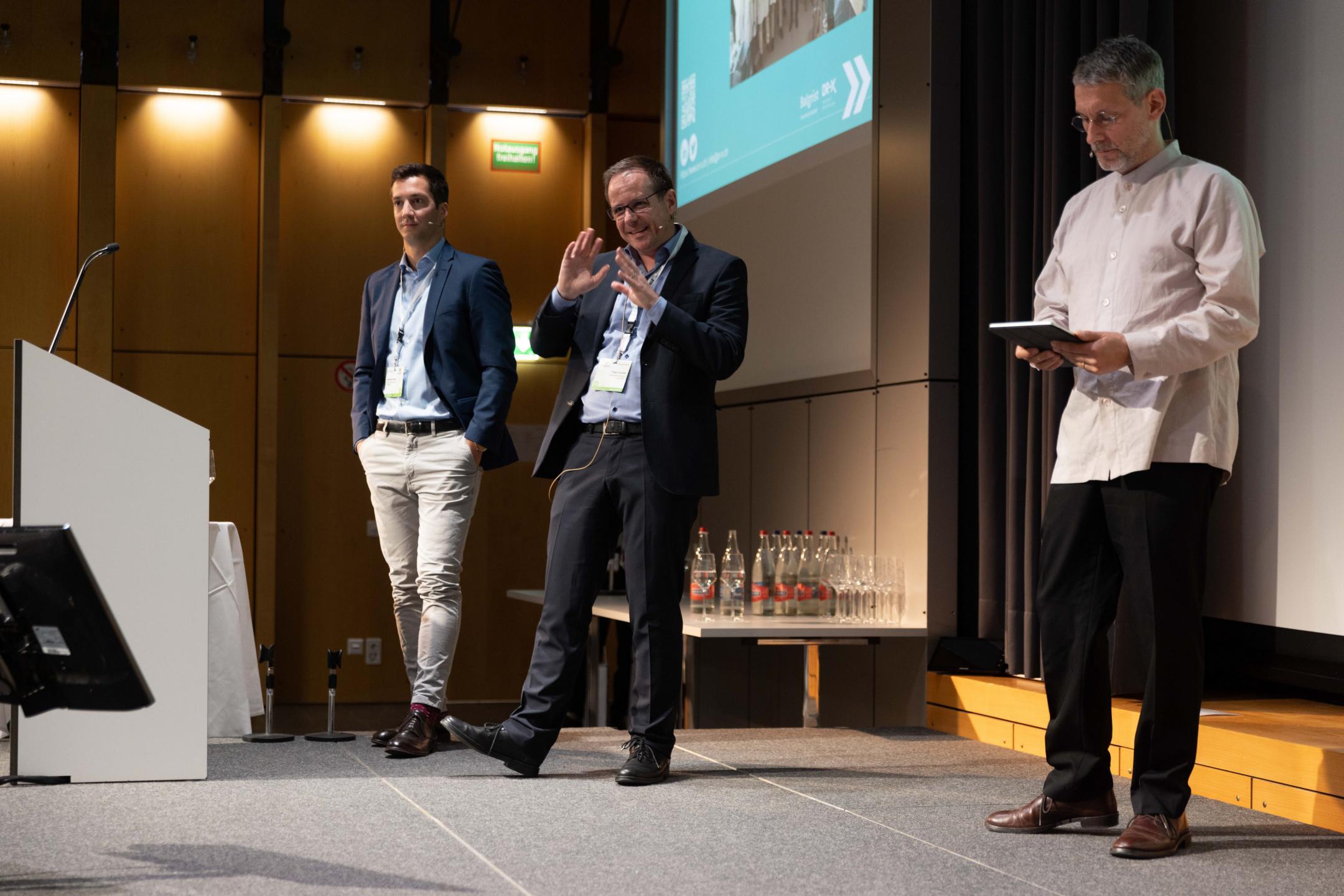 Philipp Fürnstahl & Sebastiano Caprara (Keynote Speakers) und Moderator Sven Hirsch auf dem Podium an der Life Science Zurich Impact Conference 2023