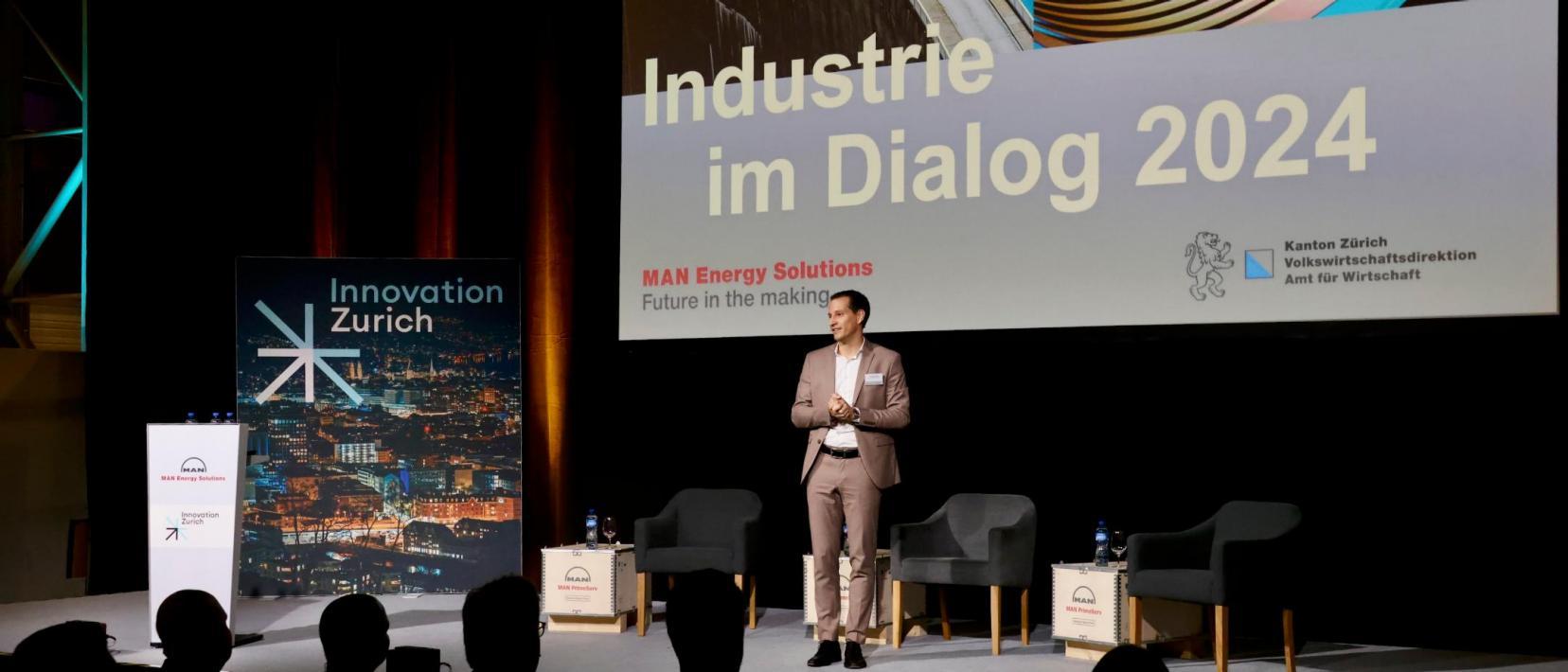 Auf der Bühne steht ein Mann und redet mit dem Publikum.