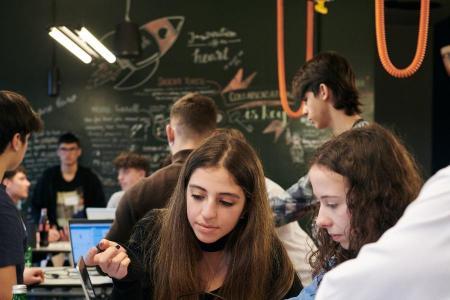 Zwei Mädchen sitzen an einem Tisch und schauen in einen Laptop