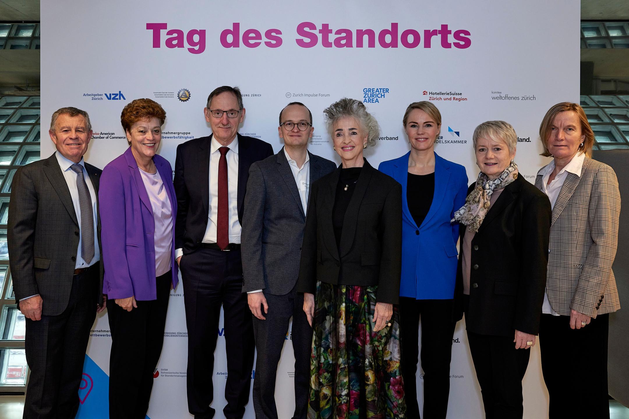 Der gesamte Zürcher Regierungsrat steht vor einer Tafel, auf der «Tag des Standorts» steht