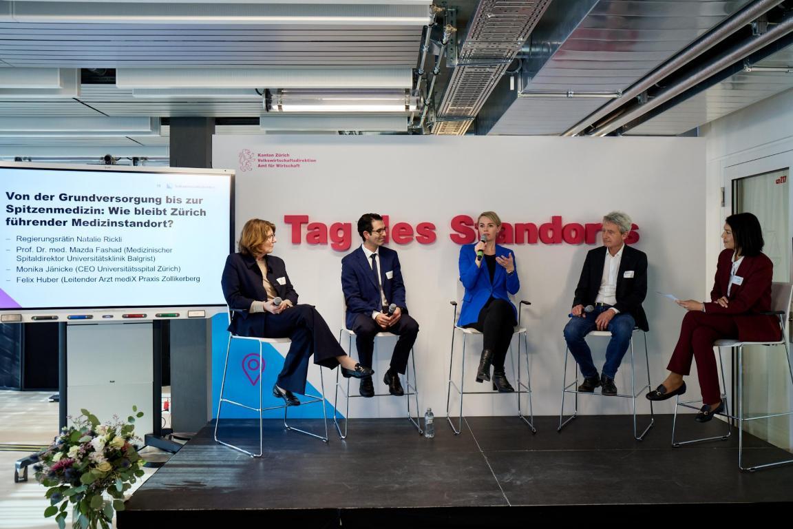 Fünf Personen sitzen auf einem Stuhl und diskutieren miteinander