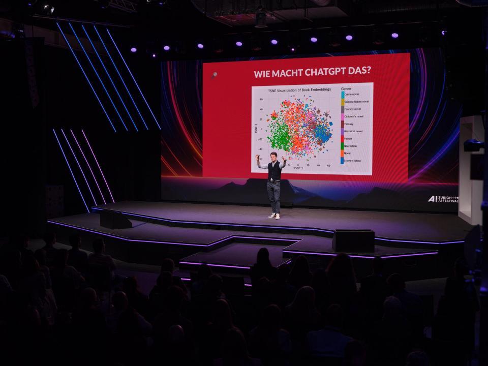 Fabian Unteregger steht auf der Bühne des Zurich AI Festivals vor einer Präsentation mit dem Titel «Wie macht ChatGPT das?» und erklärt einem grossen Publikum die Funktionsweise von Sprachmodellen.