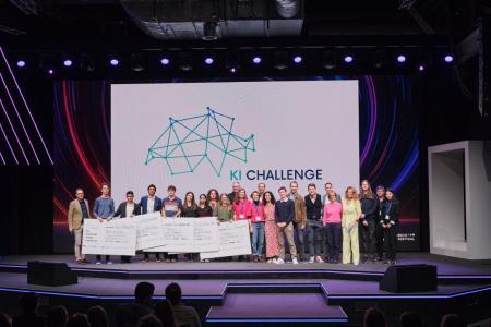 Eine grosse Gruppe von Jugendlichen, Jurorinnen und Juroren steht auf der Bühne des Zurich AI Festivals vor dem Logo der KI Challenge und hält symbolische Schecks.