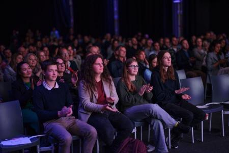 Menschen sitzen im Zuschauerraum und applaudieren während einer Veranstaltung des Zurich AI Festivals.