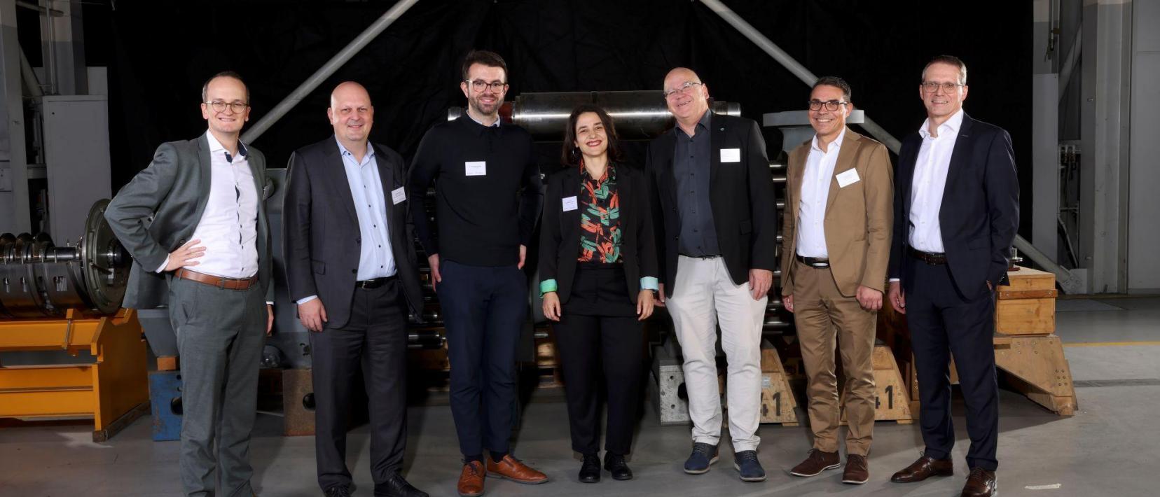 Gruppe von Personen steht in einer Industriehalle vor technischen Anlagen während des Events «Industrie im Dialog» in Zürich.