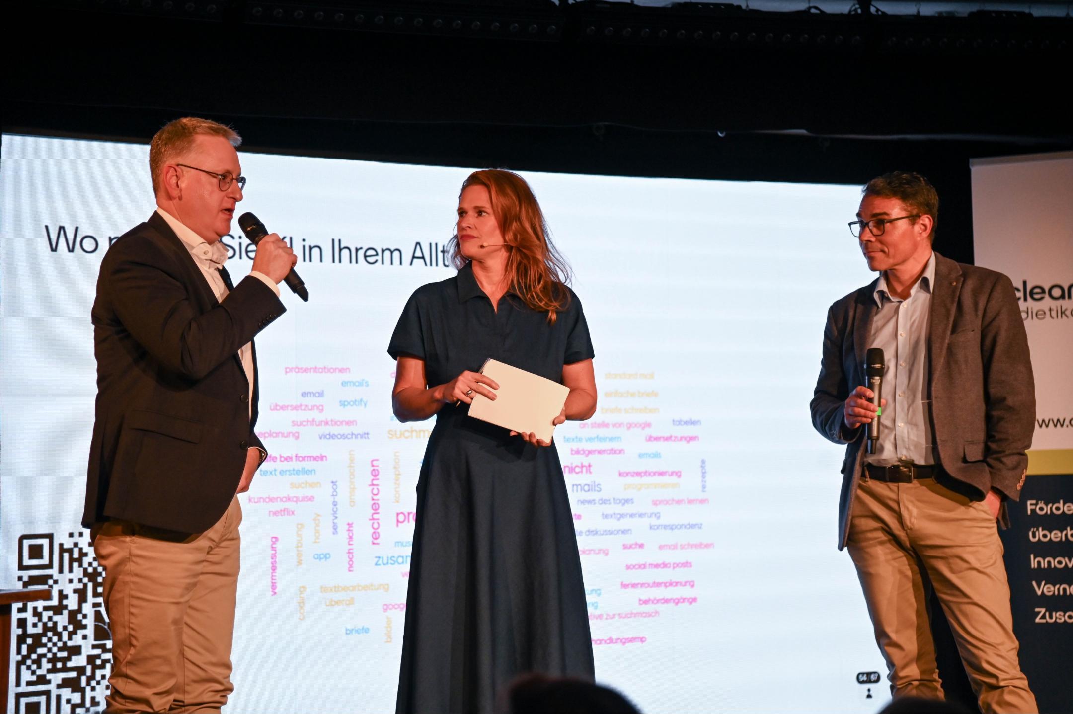 Roger Bachmann, Stadtpräsident von Dietikon, und Markus Müller, Co-Leiter der Standortförderung des Kantons Zürich, stehen gemeinsam mit der Moderatorin Kathrin Hönegger auf der Bühne.