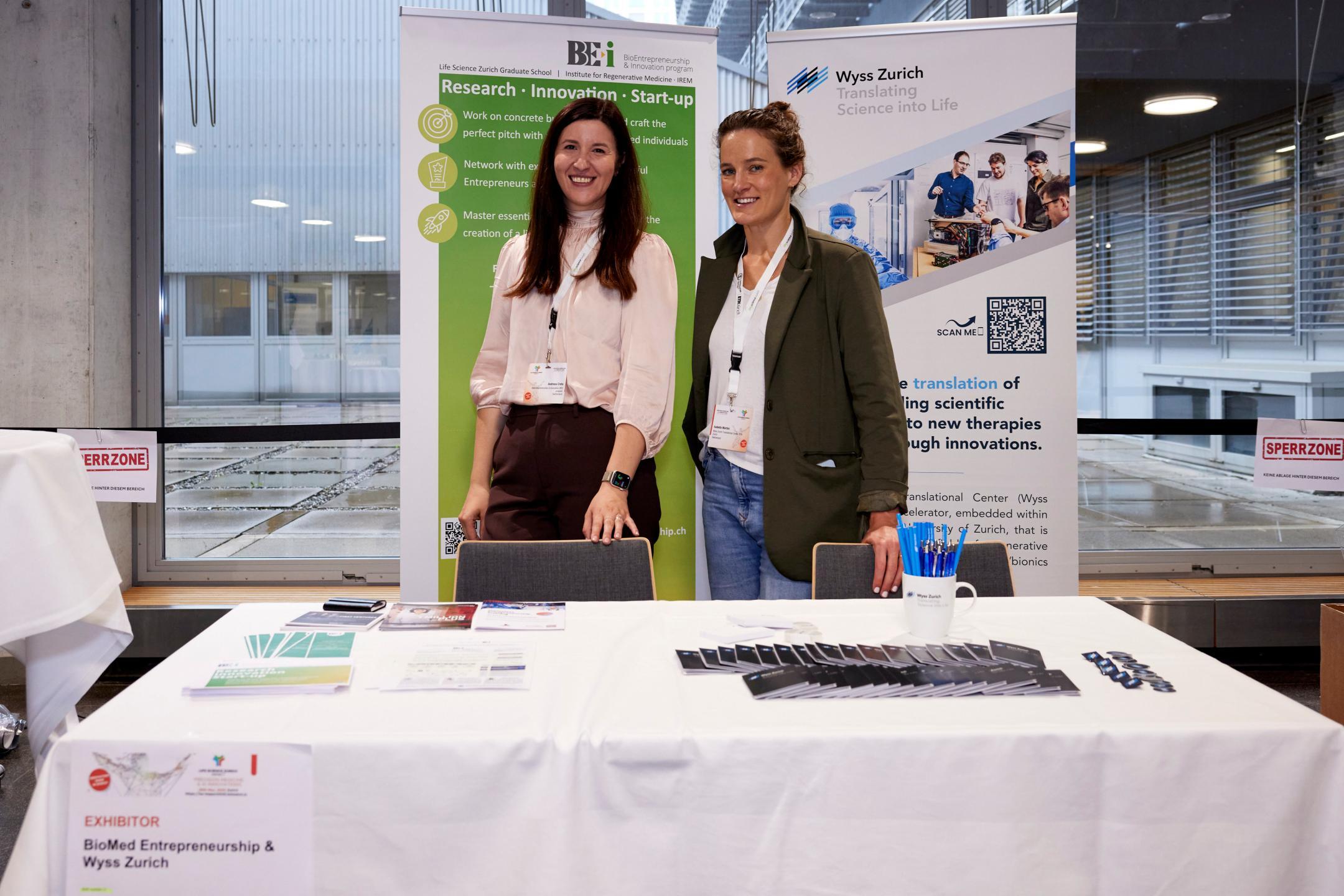 Zwei Frauen von BioMed Entrepreneurship und Wyss Zurich stehen lächelnd an ihrem Ausstellerstand
