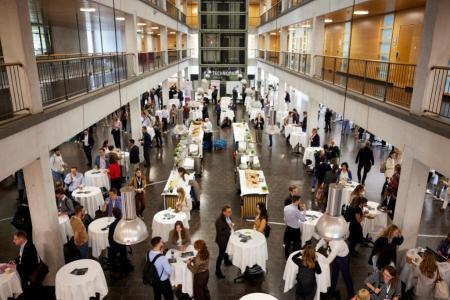 Es sind Konferenzteilnehmende in einer grossen Halle beim Networking zu sehen.