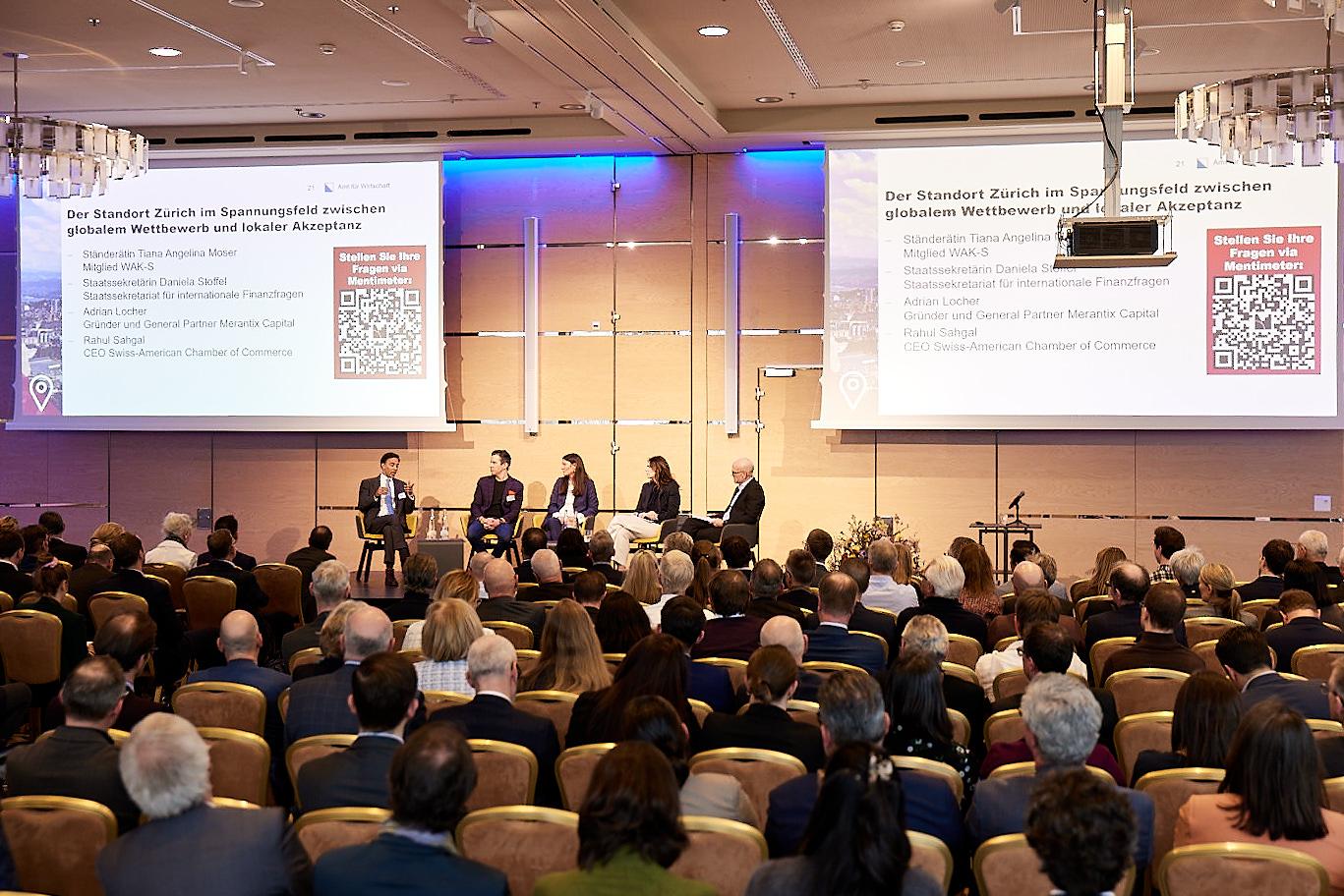 Blick in den voll besetzten Veranstaltungssaal mit Podiumsdiskussion zum Wirtschaftsstandort Zürich.