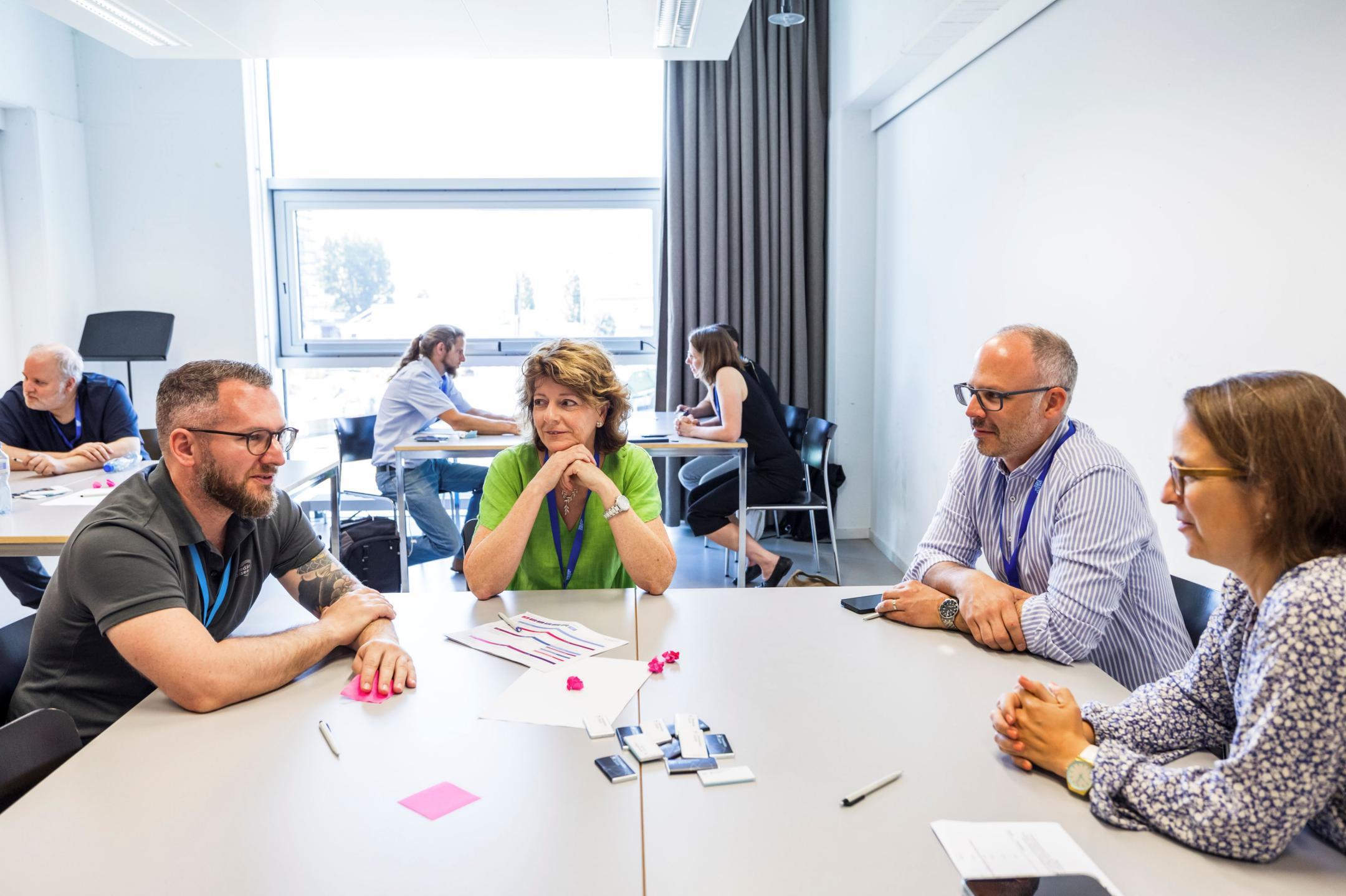 Vier Workshop-Teilnehmende sitzen um einen Tisch und tauschen sich aus 