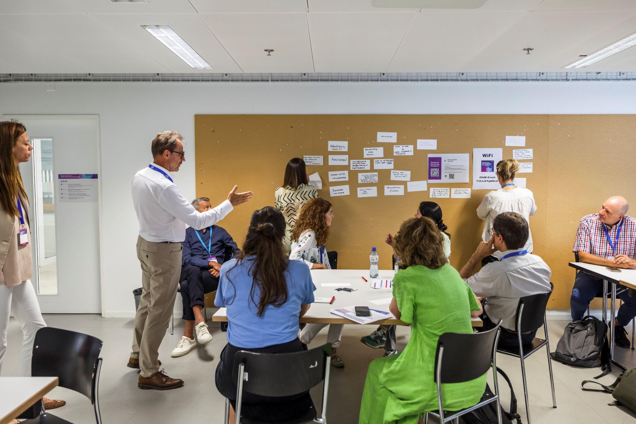 Mehrere Workshop-Teilnehmende sammeln Ideen und notieren diese auf Zetteln an der Wand