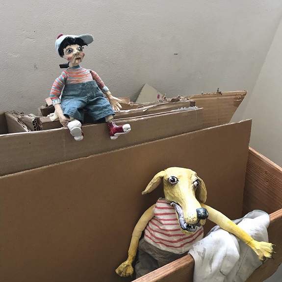 Zwei Puppen: Ein Knabe mit einer Dächlikappe und ein gelber Hund