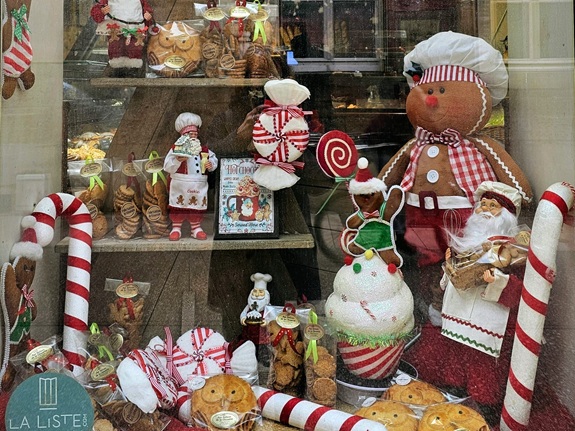 Ein Schaufenster voller Weihnachtsdekorationen und S&uuml;&szlig;igkeiten: gro&szlig;e und kleine Lebkuchenfiguren, Zuckerstangen, Pl&uuml;schfiguren als B&auml;cker und Weihnachtsmann sowie verpackte Geb&auml;ckst&uuml;cke.