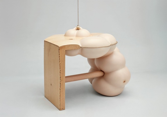Abstrakte Skulptur, bestehend aus einer einfachen L-f&ouml;rmigen Holzstruktur, an der fleischfarbene, organisch geformte Gebilde befestigt sind. 