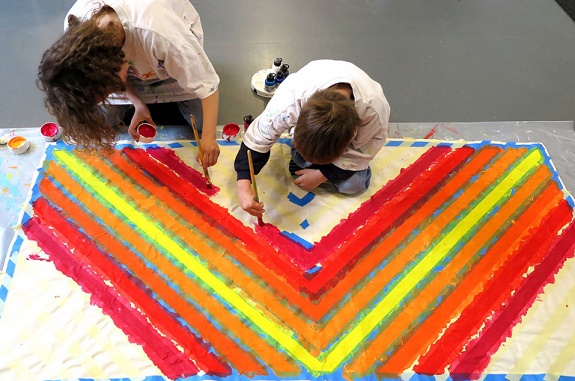 Zwei Kinder malen mit der Farbe rot