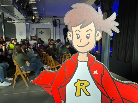 Vordergrund: Comicjunge &ndash; Hintergrund: Schulklasse verfolgt etwas konzentriert
