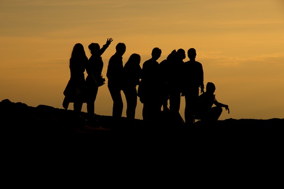 Silhouetten von Menschen auf einer Klippe bei Sonnenuntergang