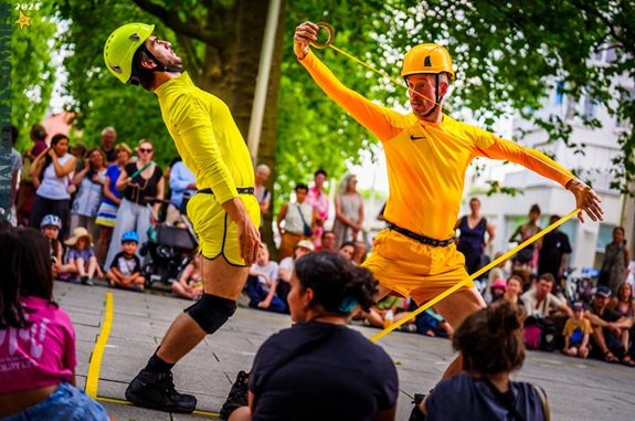 Zwei Schauspieler hantieren als Bauarbeiter mit gelbem Klebeband