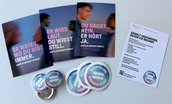 Gruppe von Menschen, die gemeinsam ein grosses Banner mit der Aufschrift &bdquo;Gegen Gewalt an Frauen&ldquo; halten. 