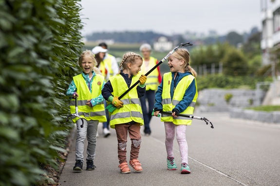 Kinder auf der Strasse mit gelben Westen und Zangen, um den G&uuml;sel aufzuklauben.