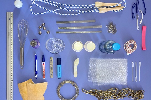 Verschiedene Alltagsgegenst&auml;nde wie Seil, Lineal und Becher sind ordentlich auf einem blauen Hintergrund ausgelegt.