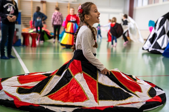 M&auml;dchen sitzt in Turnhalle - ein Reifrock ist um sie herum drapiert. 