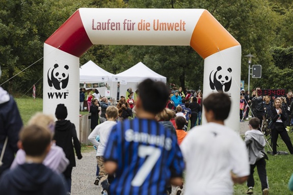 Kinder laufen bei einer WWF‑Veranstaltung durch einen Startbogen mit der Aufschrift &laquo;Laufen f&uuml;r die Umwelt&raquo;.