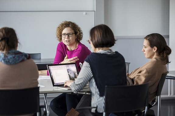 Personen sitzen an einem Tisch und diskutieren gemeinsam in einer Besprechung.