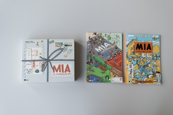 Unterlagen &laquo;MIA&raquo; (Kindergarten) mit Heften und Materialien nebeneinander auf grauem Hintergrund.