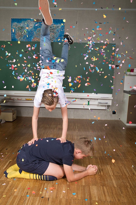 Akrobatik mit Handstand und Konfettiregen in einem Klassenzimmer.