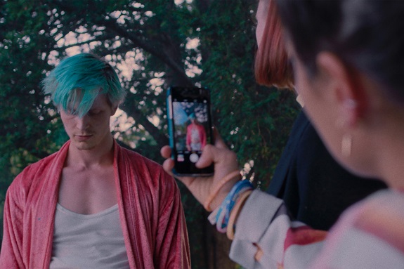 Junger Mensch filmt oder fotografiert mit dem Handy anderen jungen Menschen mit grünen Haaren