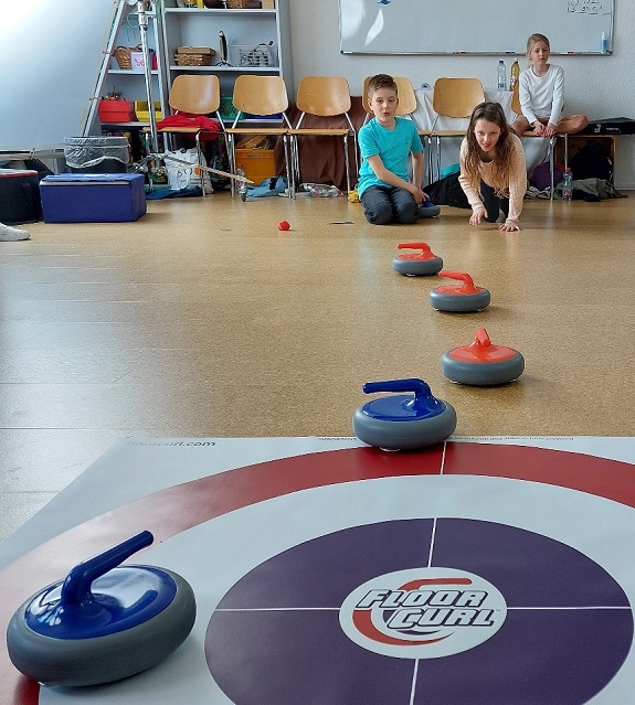 Kinder beim Curling üben im Schulzimmer